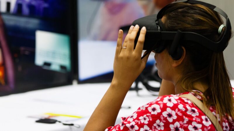 A person wears a VR headset and a flowery top