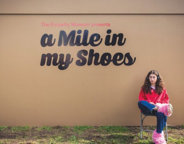 A photograph from A Mile in My Shoes with a young woman sitting on a chair with fluffy shoes on