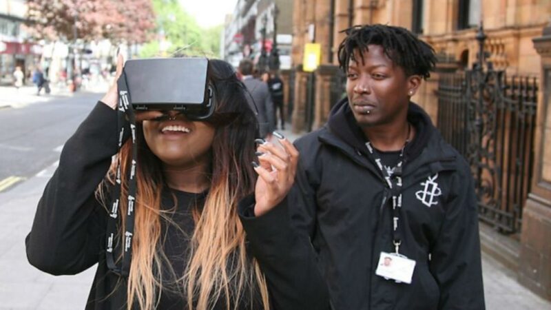 Woman using VR headset with man looking on