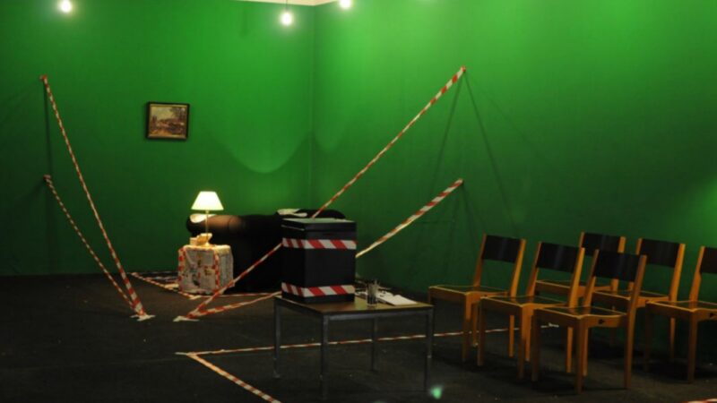 A green room with chairs and furniture covered in tape