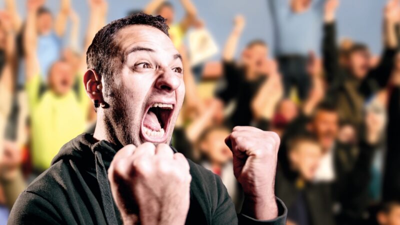 A photograph of a man with his fists up cheering