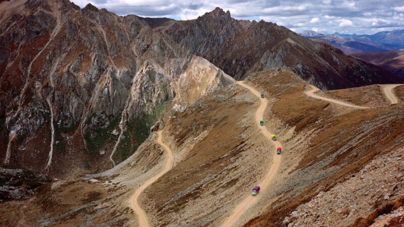 A photograph of a mountainous road with cars travelling on it