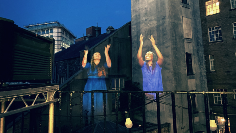 A photograph of a builder with two people projected onto it digitally