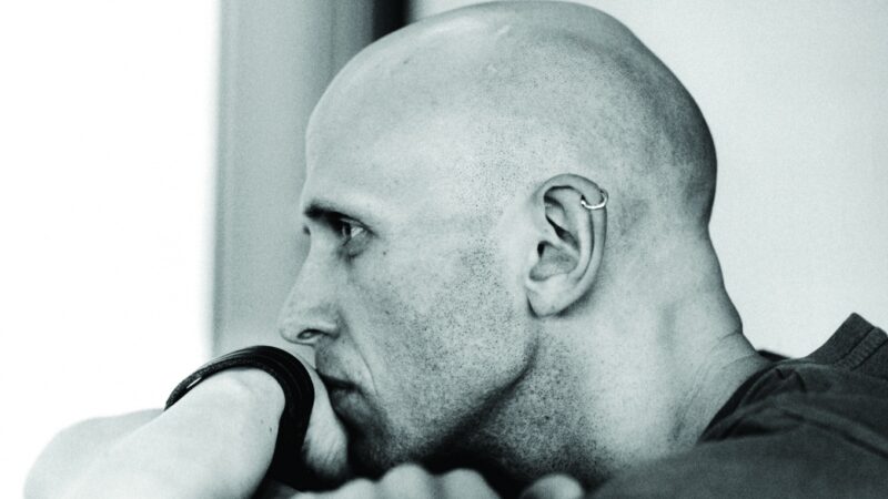 A photograph of the side profile of a bald man
