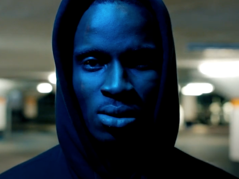 A dark skinned man wearing a hood
