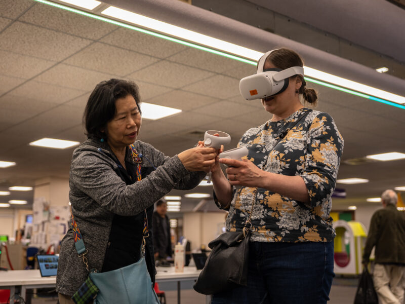 An east asian woman assists a white woman with a handset