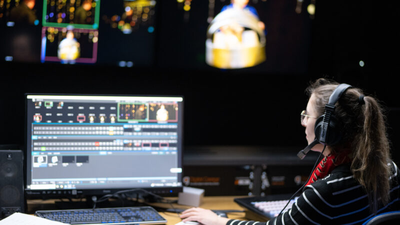 A woman sits at a screen editing footage