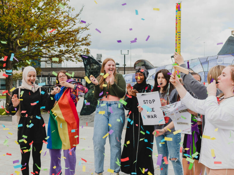 Young women from different backgrounds standing together to protest.
