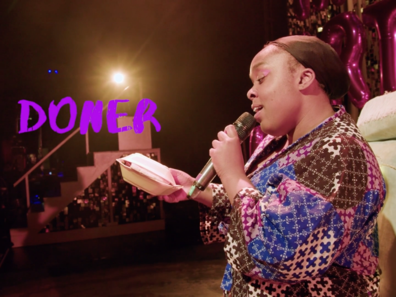 Photo of the character Lady in the stage show, singing to a kebab in her dressing gown.