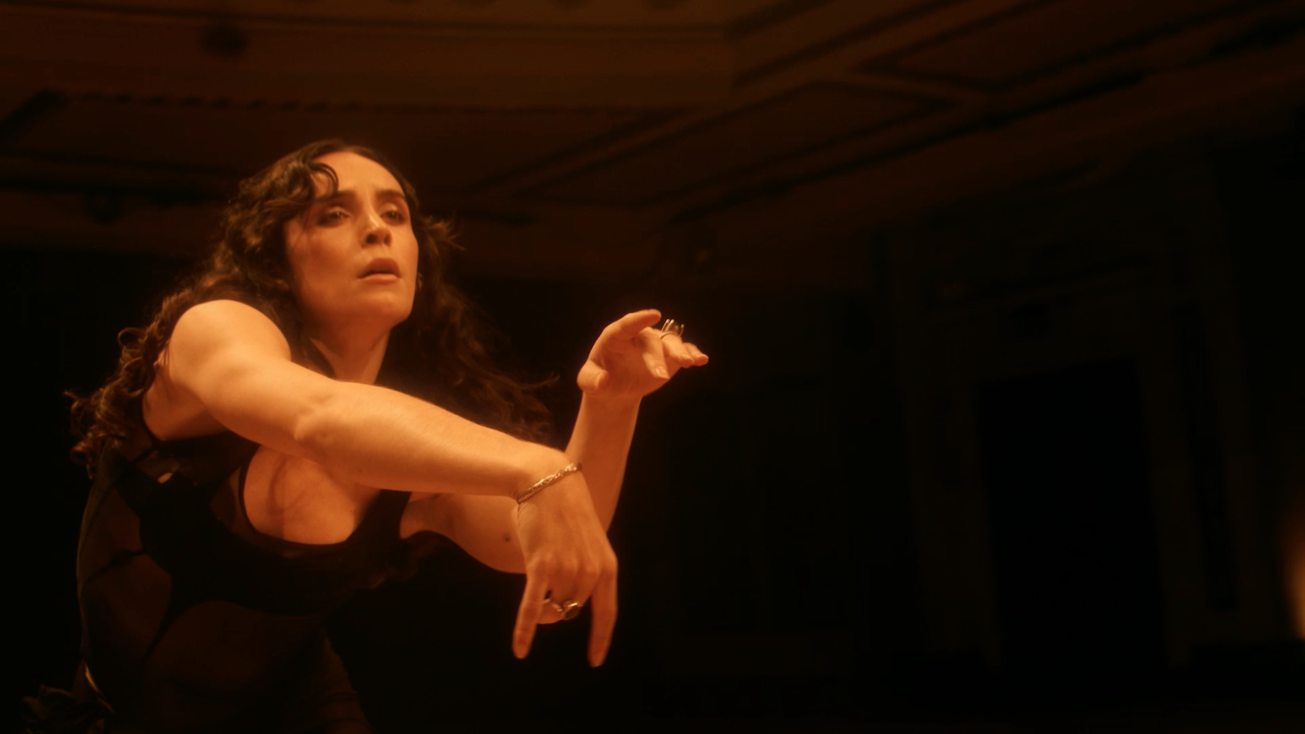 Photo of a dancer in a black dress with her arms outstretched.
