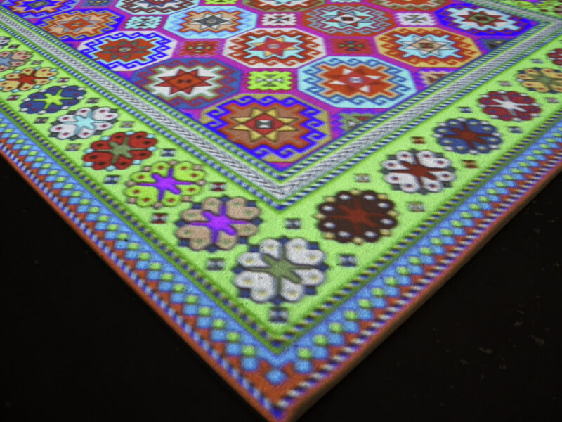 Photo of the corner of a light projection of an Islamic rug.