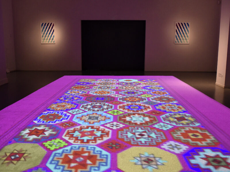 Photo of a light projection of a colourful Islamic rug.