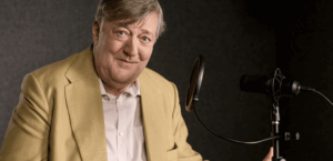 Sir Stephen Fry sits at a microphone