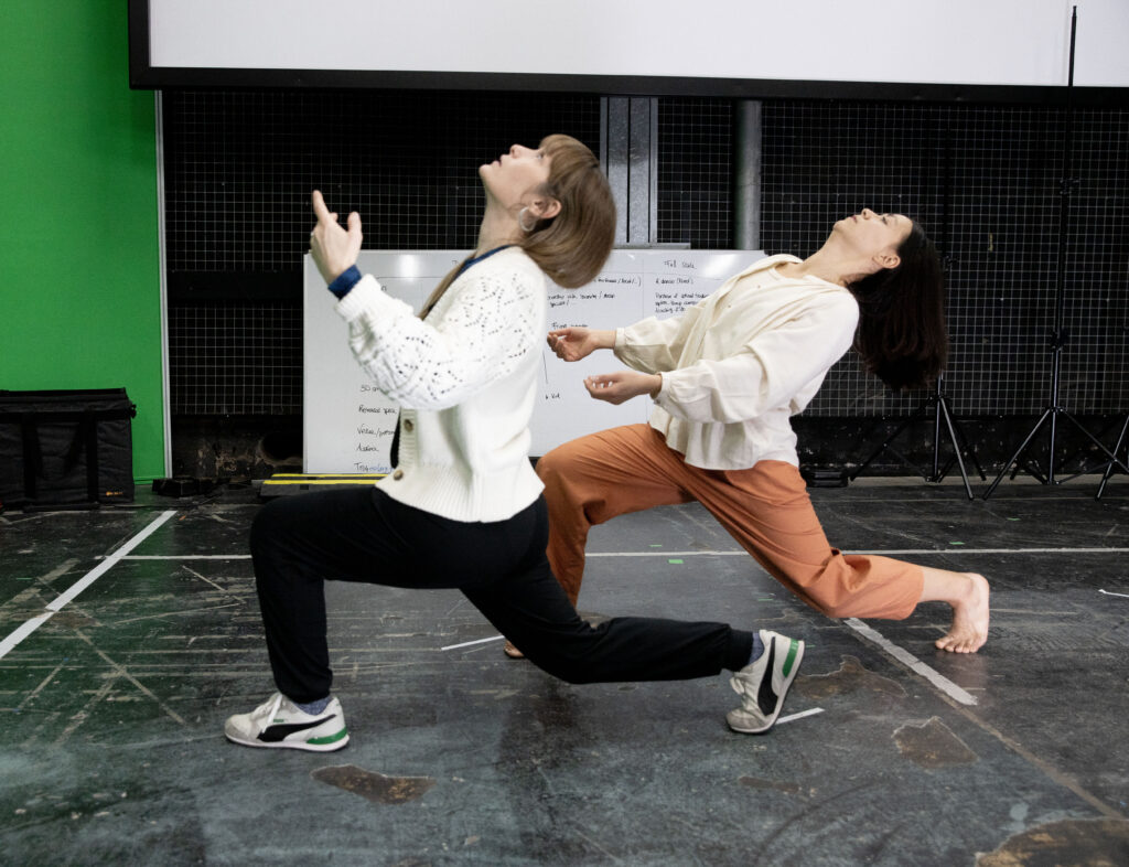 Image of two dancers in rehearsal, both kneeling