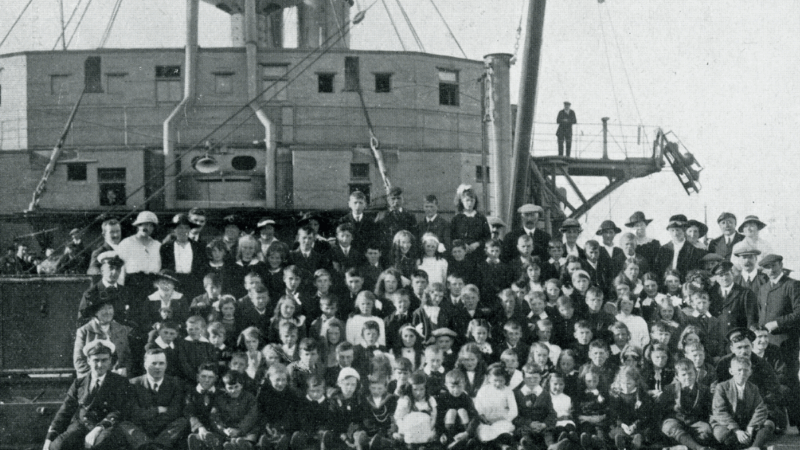 A black and white historical image of children in front of a military naval vehicle.