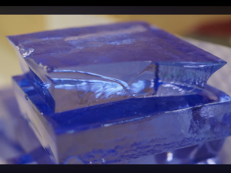 Close-up of a stack of roughly-cut vibrant blue glass tiles.
